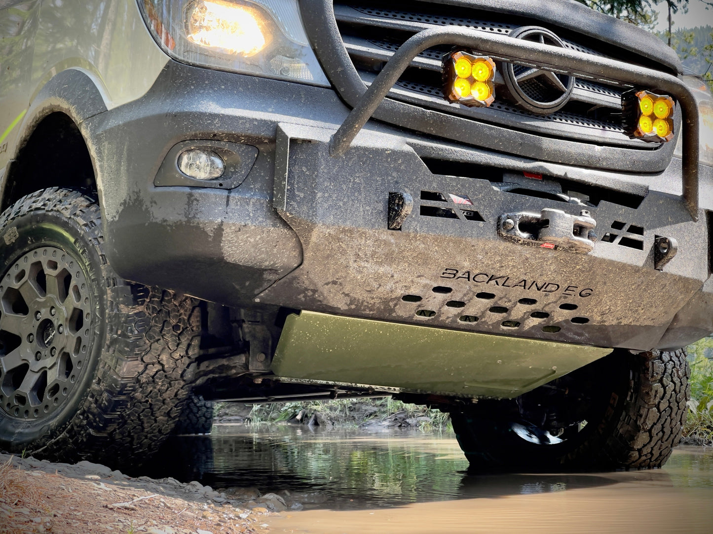 Close up of a van with a BISON Series 4X4 Engine Sprinter Skid Plate going through rocks and mud.